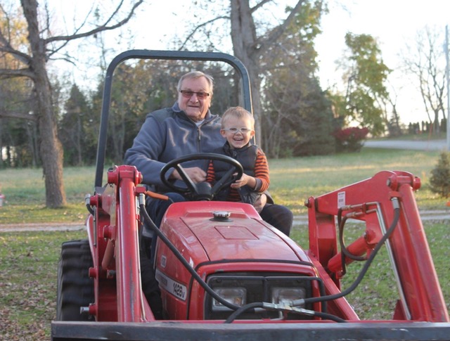 Papa Tom on the tractor with his grandson